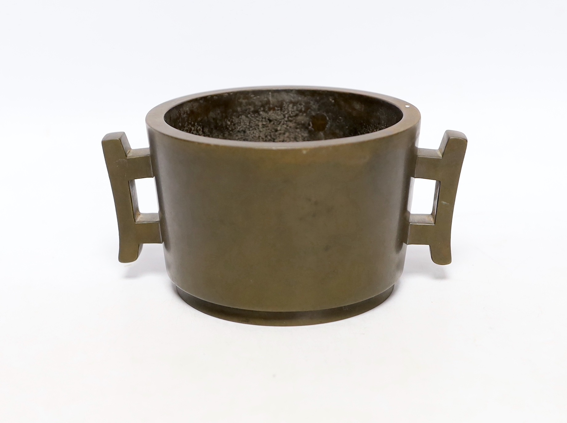 A Chinese bronze censer, of tapering cylindrical form, applied with a pair of trellis shaped handles, cast four character mark, 16cm wide